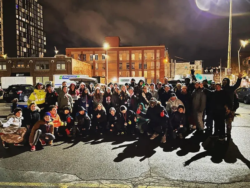 A large group of believers gathered at night on a city street for outreach