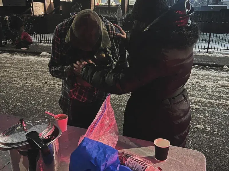 Two people praying together on a winter street during outreach