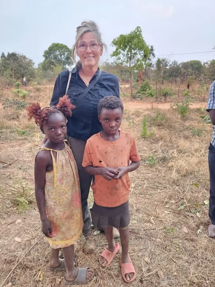 Terra Nicolle standing outdoors with two children during her time in Africa